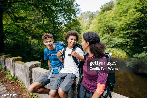 family resting on stone bridge during hike - purple shirt stock-fotos und bilder