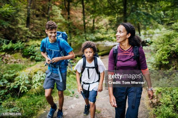 family of three walking woodland trail together - females hiking stock pictures, royalty-free photos & images