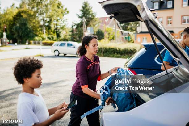 mother putting rucksacks in car trunk after hiking with sons - purple boot stock pictures, royalty-free photos & images