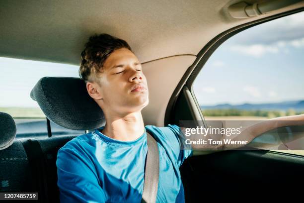 young man sleeping in car after busy day of hiking - car back seat stock pictures, royalty-free photos & images