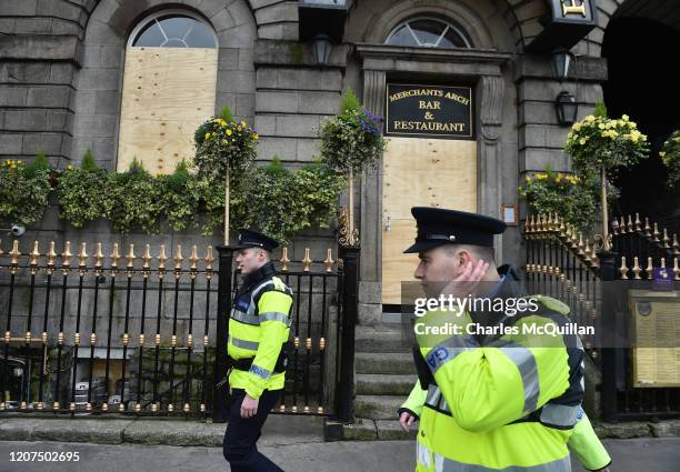 Police officers walk past a boarded up bar following the cancellation of the annual Saint Patricks Day parade and celebrations on March 17, 2020 in...