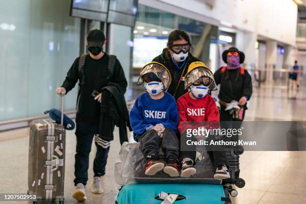 Travellers wearing protective equipment, as a precautionary measure against the COVID-19 coronavirus, enter the arrival hall at the Hong Kong...