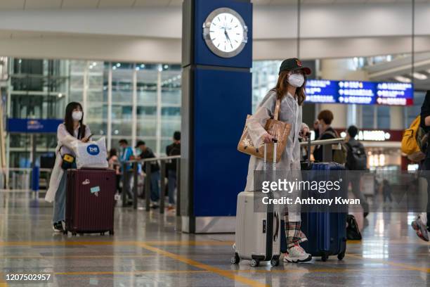 Travellers wearing protective equipment, as a precautionary measure against the COVID-19 coronavirus, enter the arrival hall at the Hong Kong...