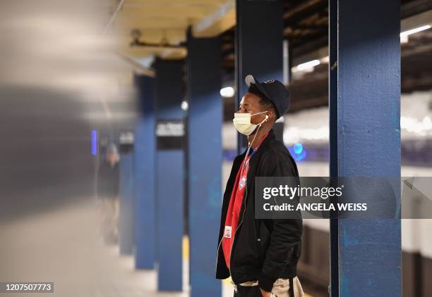 Man with a face mask stands at the subway station on March 17, 2020 in the Brooklyn Borough of New York City. - The coronavirus outbreak has...