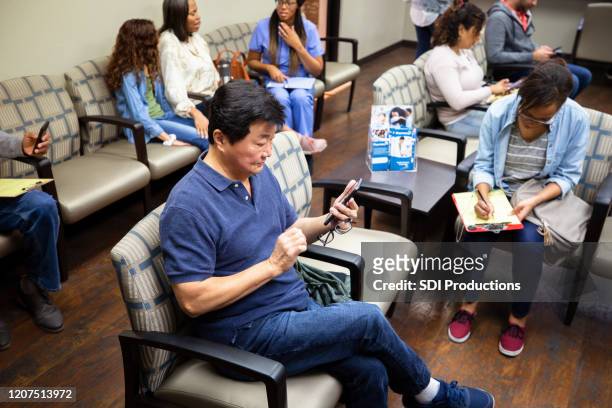 l'anziano asiatico aspetta l'appuntamento con il medico - huddle foto e immagini stock