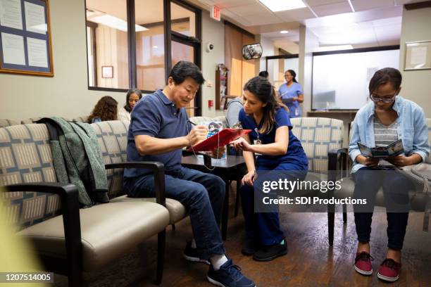 helpful nurse helps senior man with medical paperwork - er visit stock pictures, royalty-free photos & images