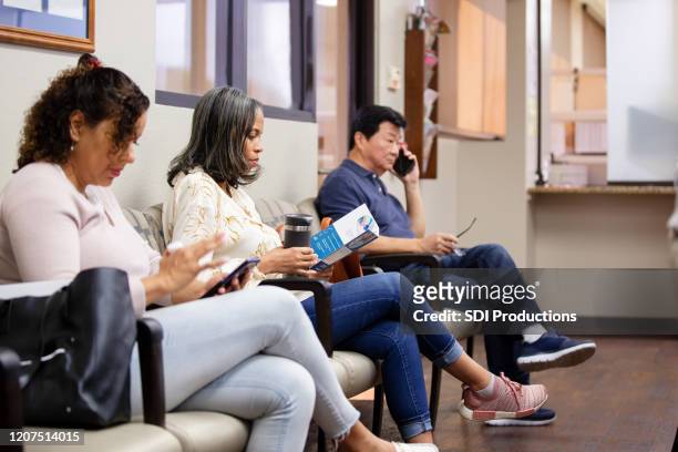 de rijpe vrouw leest brochure terwijl het wachten op medische benoeming - wachtkamer stockfoto's en -beelden
