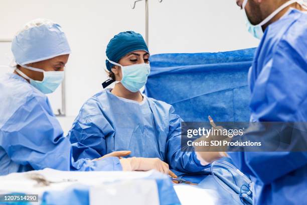 krankenschwester konzentriert sich auf schnitt, während arzt nach instrument fragt - ambulante behandlung stock-fotos und bilder