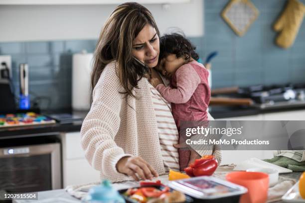 mother holding baby and multi-tasking in kitchen - mãe dona de casa imagens e fotografias de stock