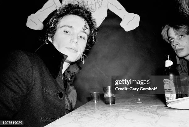 View of English New Wave musician Adam Ant , of the group Adam and the Ants, sits with an unidentified man at the Mudd Club, New York, New York,...