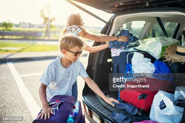 kinderen die helpen om de familieauto voor reis te verpakken. - pak stockfoto's en -beelden