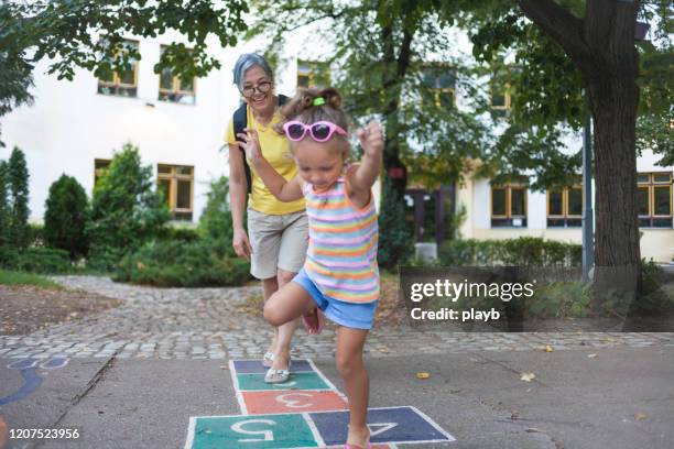 grandma and granddaughter having fun outdoors - hopscotch stock pictures, royalty-free photos & images