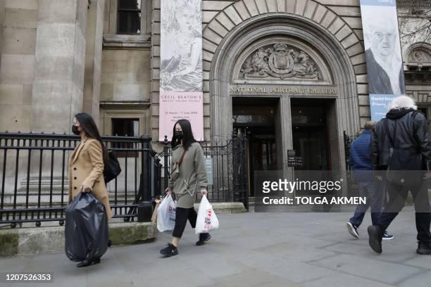 Pedestrians wearing face masks walk past the National Portrait Gallery in central London on March 17, 2020 after it was announced that the gallery...