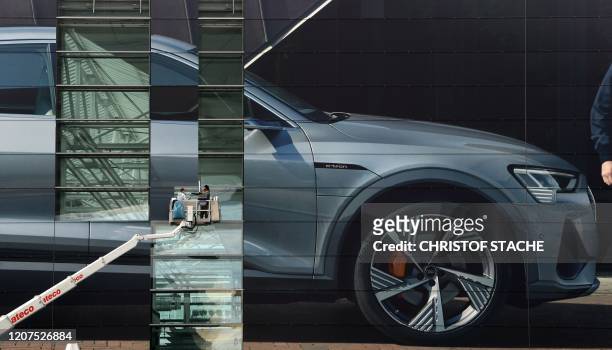 Workers put up an giant advertisement by the German automobile manufacturer Audi to the outside of a terminal at Franz Josef Strauss Airport in...
