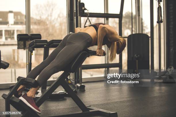 woman lifting a weight to work out her lower back muscles - lower back stock pictures, royalty-free photos & images