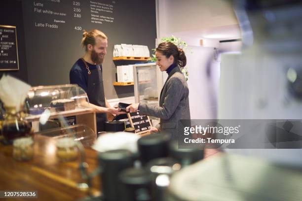 klant die contactloos met een smartphone in een koffiewinkel betaalt. - coffee shop owner stockfoto's en -beelden