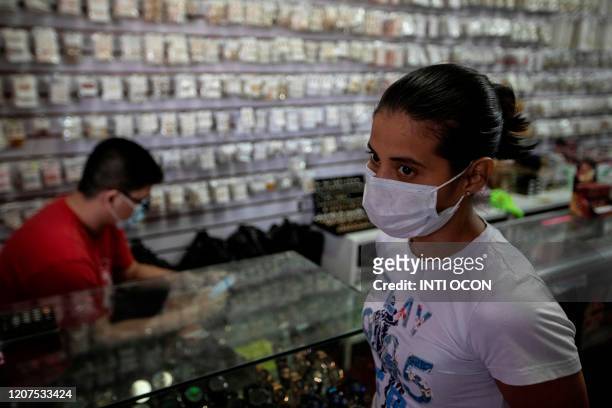 People wear face masks as a precautionary measure against the spread of the new coronavirus, COVID-19, at a market in Managua, on March 17, 2020. -...