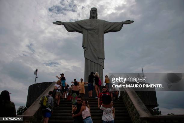 Tourists visit the statue of Christ the Redeemer atop Corcovado hill in Rio de Janeiro, Brazil, on March 17, 2020. - Rio de Janeiro's state...