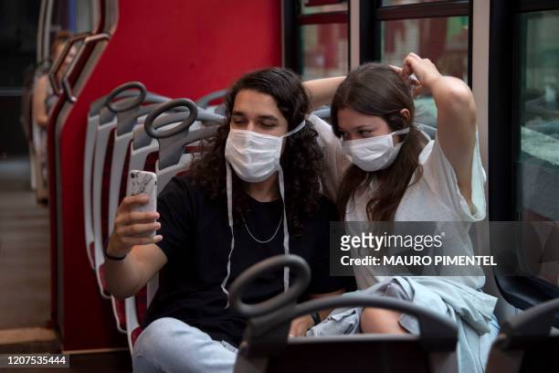 Tourists make a selfie wearing face masks onboard the Corcovado hill train, on their way up to see the statue of Christ the Redeemer in Rio de...