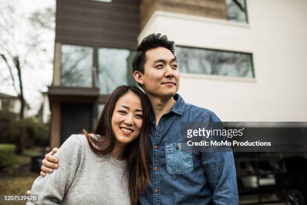 portrait of young couple in front of new home - couple photos et images de collection