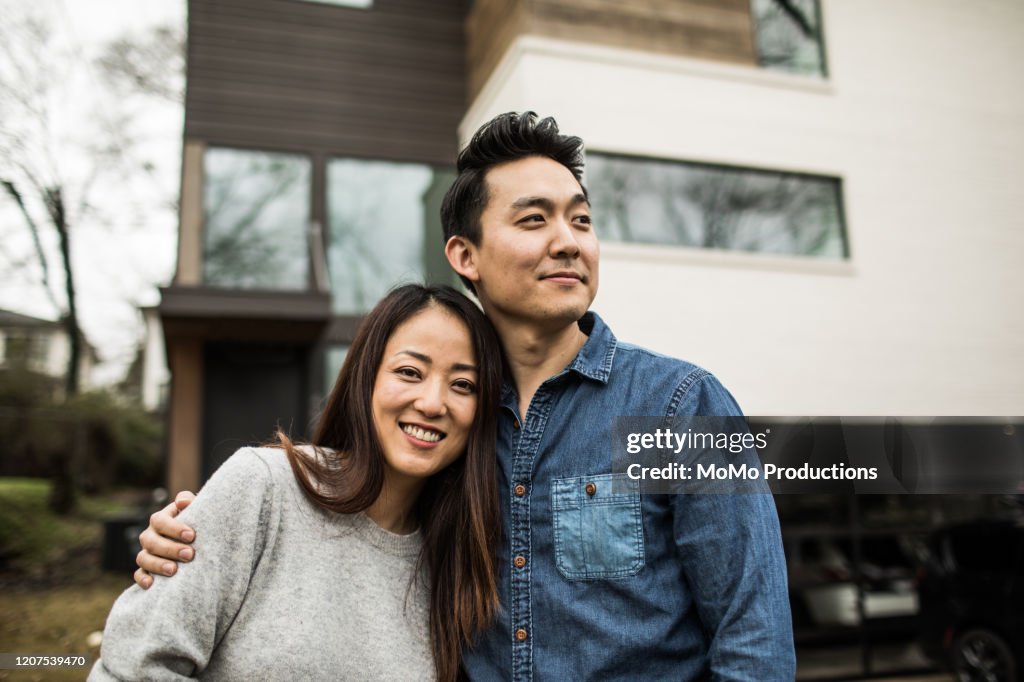 Portrait of young couple in front of new home