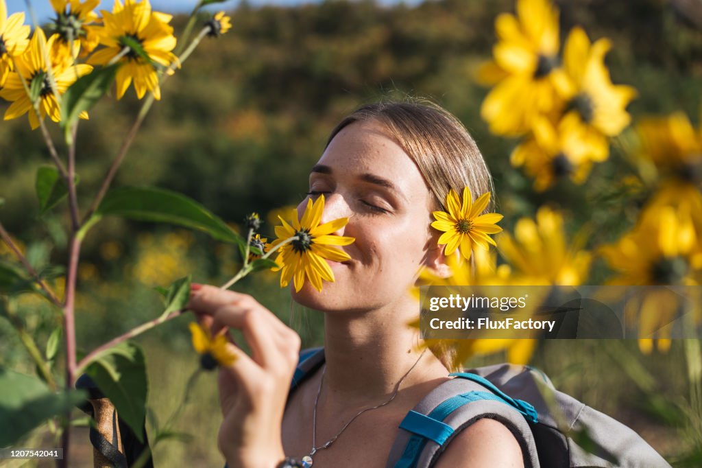 Beautiful female hiker smelling wild flowers and enjoying the scent of nature
