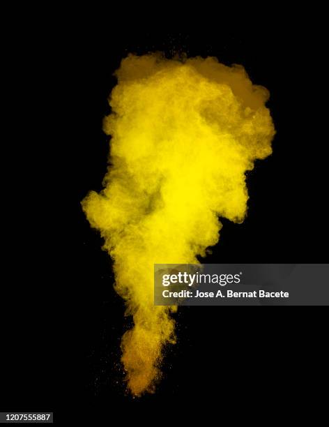 explosion by an impact of a cloud of particles of powder and smoke of yellow color on a black background. - yellow smoke stock pictures, royalty-free photos & images