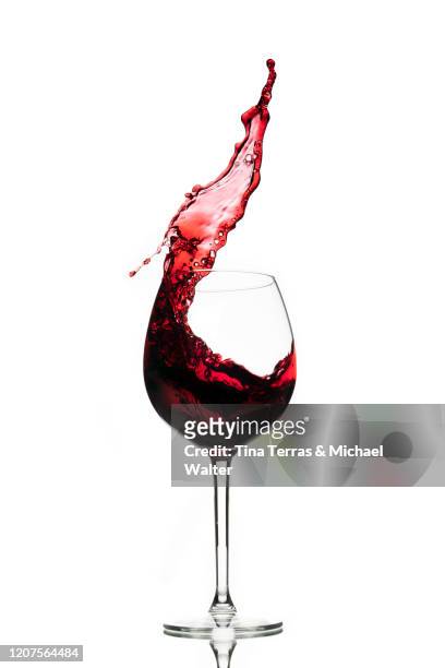 red wine splashing in glass against white background. copy space. - red wine foto e immagini stock