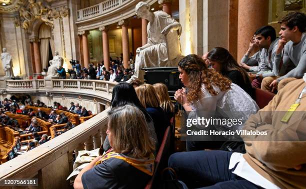Young woman prays with a rosary while following deputies as they cast their nominal votes at the Assembleia da Republica during the debate in which...