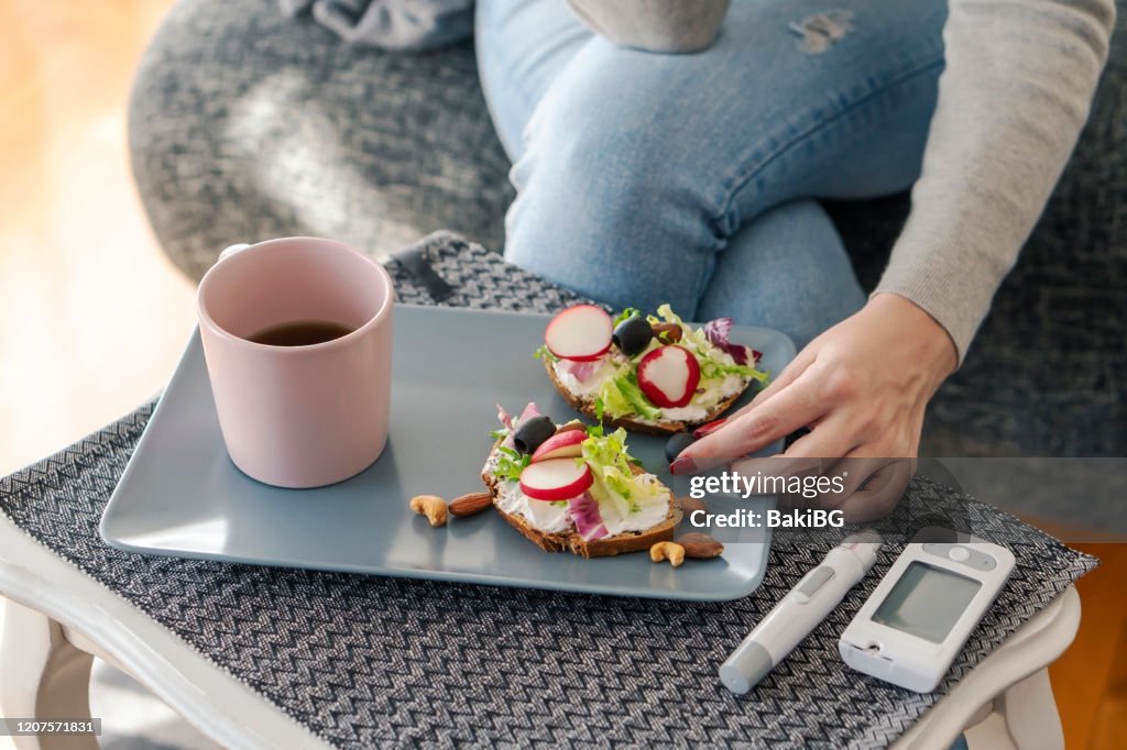 Ung diabetiker kvinna som äter frukost hemma