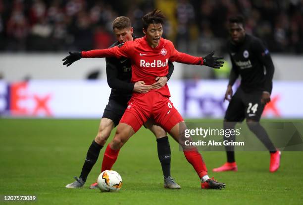 Hwang Hee-chan of RB Salzburg is tackled by Erik Durm of Eintracht Frankfurt during the UEFA Europa League round of 32 first leg match between...