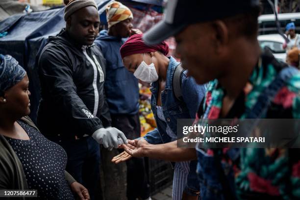 Man sprays commuters with hand sanitiser as a preventive measures at Wanderers taxi rank in Johannesburg CBD, on March 18, 2020. African countries...