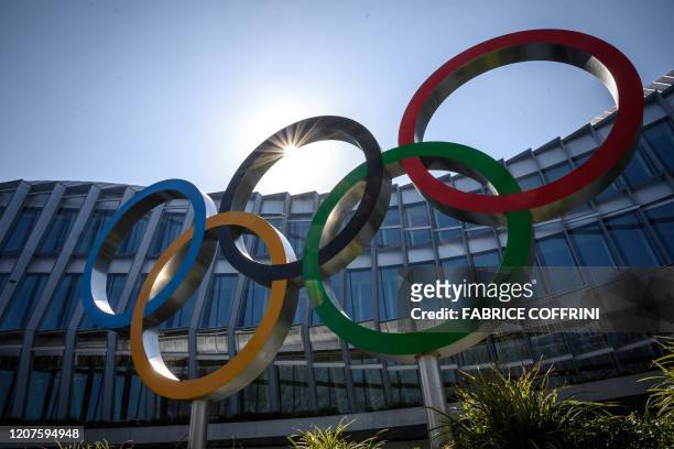 The Olympic Rings logo is pictured in front of the headquarters of the International Olympic Committee in Lausanne on March 18 as doubts increase...