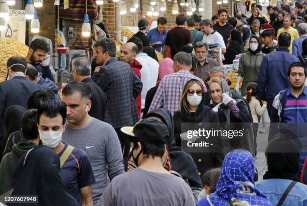 Iranians, some wearing protective masks, gather inside the capital Tehran's grand bazaar, during the Covid-19 coronavirus pandemic crises, on March...