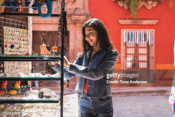 young woman shopping for jewlery along historic street - mexican street market stock pictures, royalty-free photos & images