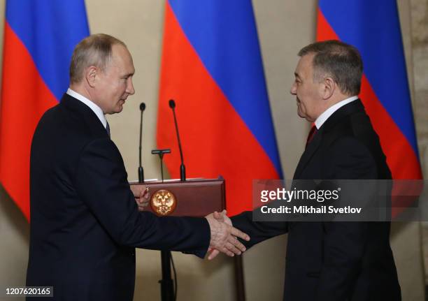 Russian President Vladimir Putin shakes hands with billionaire and businessman Arkady Rotenberg during the awarding ceremony at the museum on March...