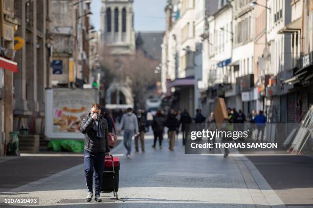 People walk in a shopping street of Saint-Denis, near Paris on March 18 after a strict lockdown came into effect in France to stop the spread of the...