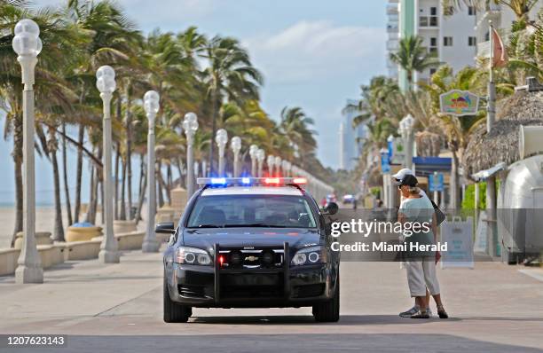 Hollywood Beach Police talks with visitors at Hollywood broadwalk which is one of the many places that are not open to the public due to the closure...