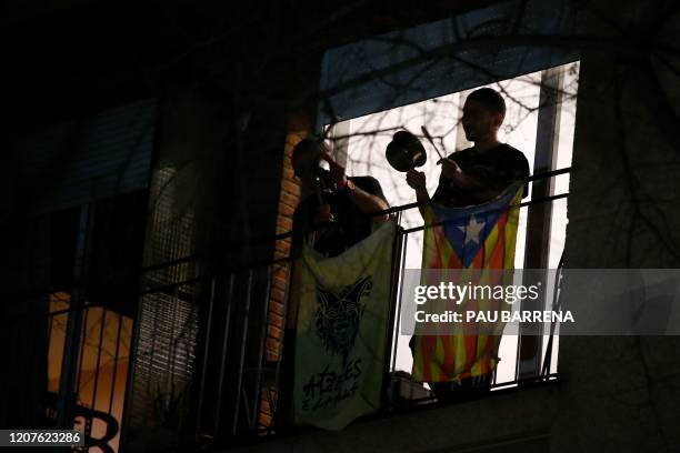 People bang on pots and frying pans from their balconies on March 18, 2020 in Barcelona as part of a protest against the Spanish monarchy, at the...