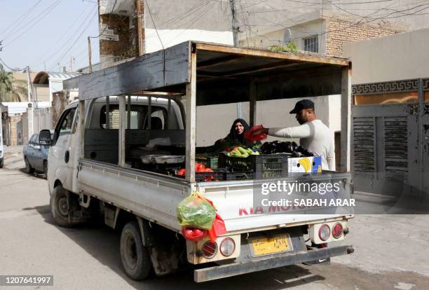 An Iraqi man sells vegetables on the back of his pick-truck at a residential neighbourhood in Baghdad on March 19, 2020 amidst measures to fight the...