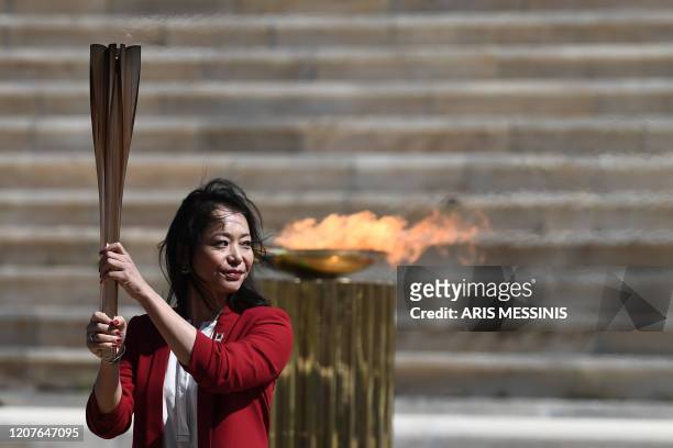 Former Japanese swimmer Imoto Naoko holds the Olympic torch during the olympic flame handover ceremony for the 2020 Tokyo Summer Olympics, on March...