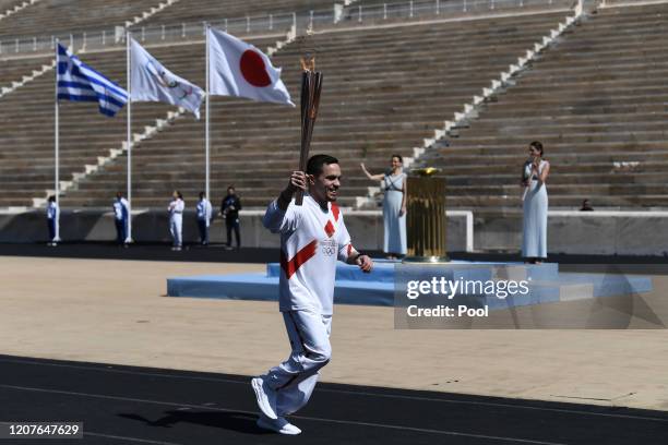 An Athlete carries the Olympic torch during the Flame Handover Ceremony for the Tokyo 2020 Summer Olympics on March 19, 2020 in Athens, Greece. The...