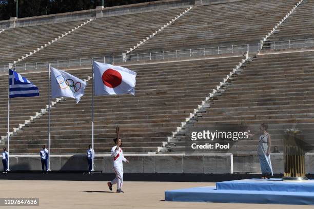 An Athlete carries the Olympic torch during the Flame Handover Ceremony for the Tokyo 2020 Summer Olympics on March 19, 2020 in Athens, Greece. The...