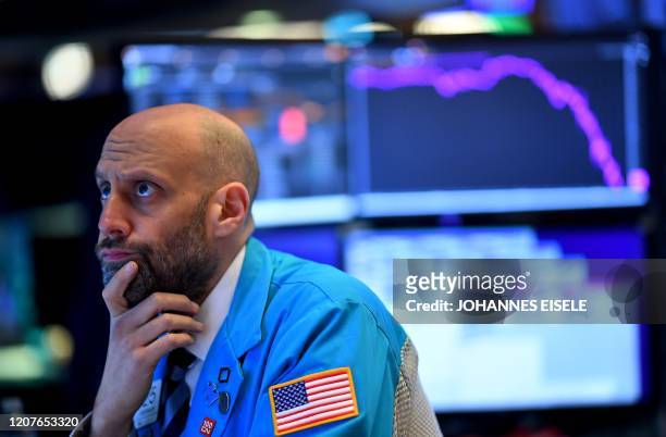 Traders works during the opening bell at the New York Stock Exchange on March 19 at Wall Street in New York City. - US stocks open mixed, Dow -0.4%,...