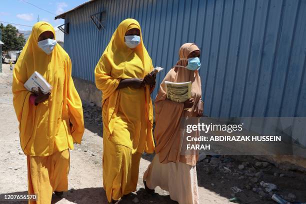 Students walk in a Mogadishu neighbourhood wearing face masks as protective measure against Coronavirus on Thursday March 19, 2020. Somali prime...