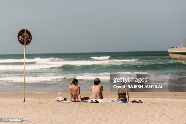 Beachgoers sunbathe on March 19, 2020 at the north beach in Durban as the eThekwini Municipality places drastic measures to be imposed in all beaches...