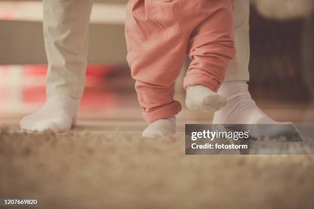 moeder die haar babydochter helpt lopen rond haar kinderdagverblijf - learning to walk stockfoto's en -beelden