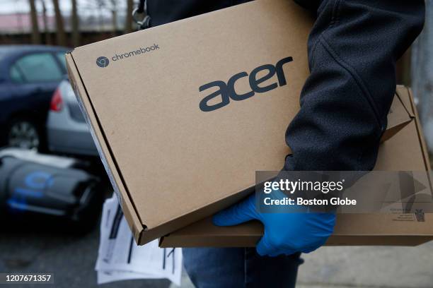 Boston Public Schools employee Giscar Centeio holds two laptops as he does a dry run going door to door handing out Acer chromebooks to students in...