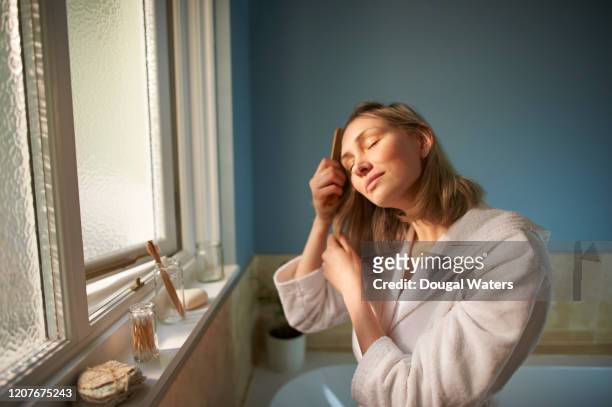 woman brushing hair in bathroom with plastic free brush. - brushing hair stock pictures, royalty-free photos & images