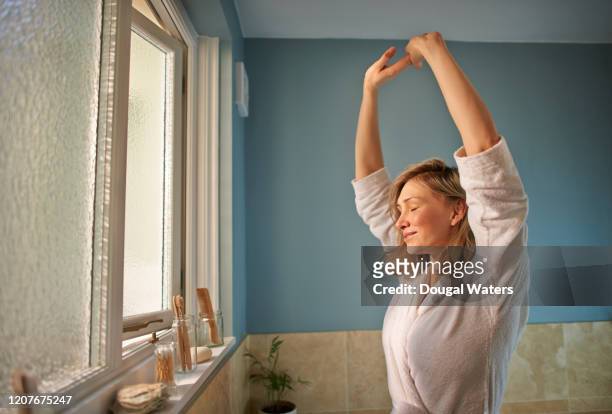 woman stretching arms with eyes closed in morning bathroom. - woman waking up happy stock pictures, royalty-free photos & images